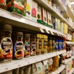 Shelves with distinct Shoppers Drug Mart pricing and sales stickers. Shelves are stocked with coffee and tea.