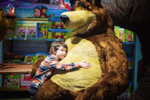 A 6-year old boy hugs a huge plush bear