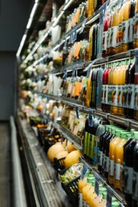 Long view of grocery store shelves showing cold items such as juice and fruits